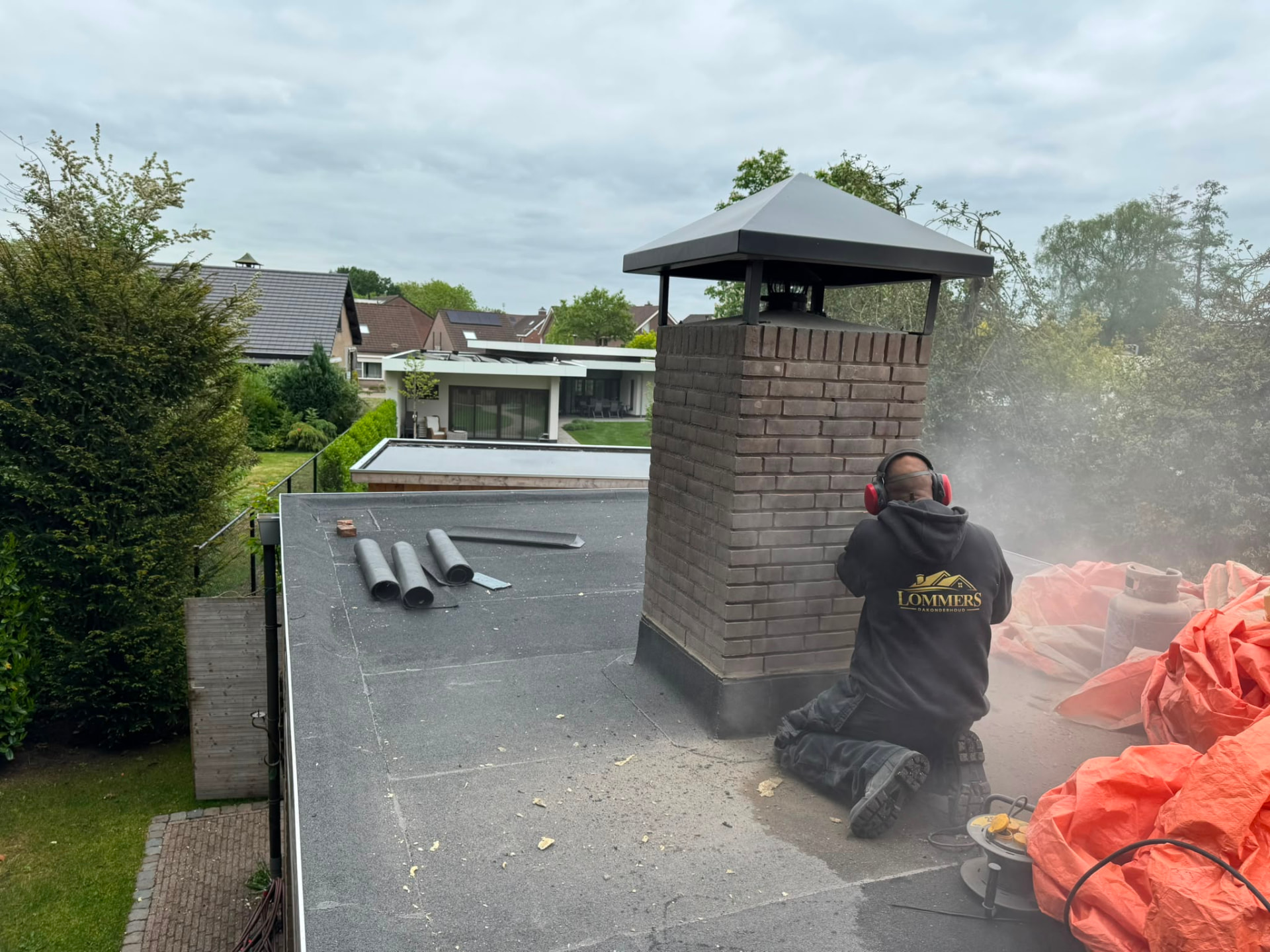 Kees Lommers werkt aan een schoorsteen op een plat dak in Berghem